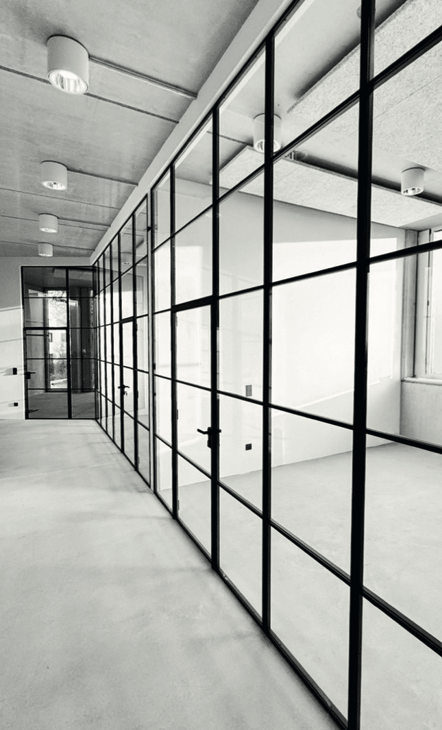 Großflächige Stahl-Glas-Trennwände als Büroabtrennung in modernem Großraumbüro