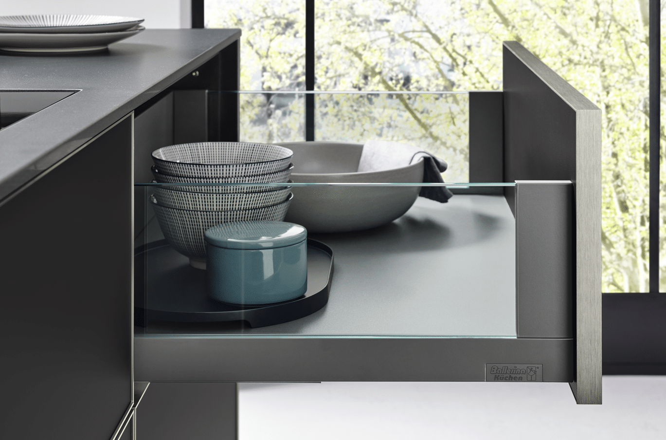 Eckküche mit geöffneten Auszügen und Keramikgeschirr auf dunkler Arbeitsfläche