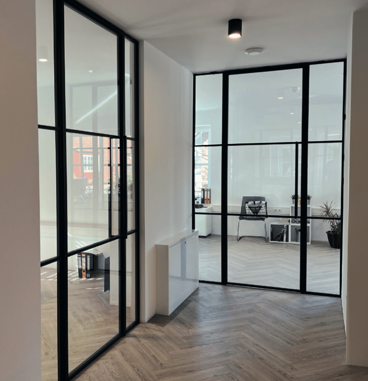 Raumhohe Stahl-Glas-Tür mit schwarzem Profil als Büroeingang in modernem Gebäude