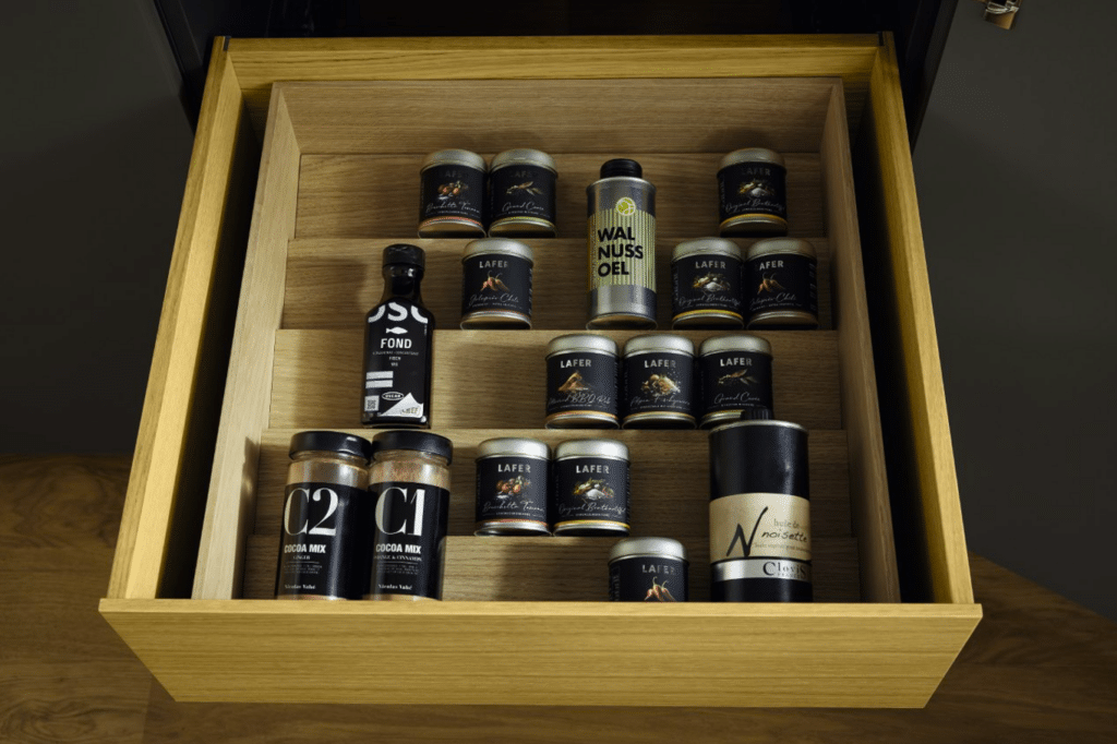 Geöffnete gelbe Küchenschublade mit sortierten Gläsern und Vorräten